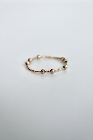 gold fidget spinner ring with gold beads on a white background