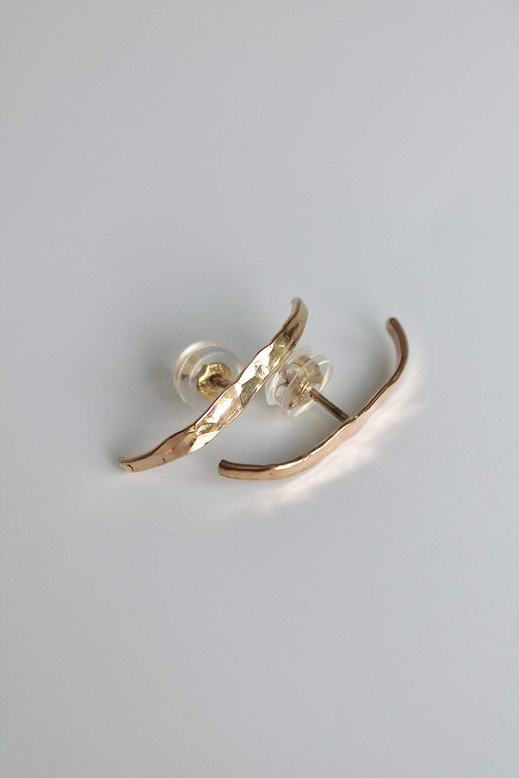 Gold earrings on a light gray background