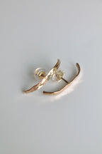 Gold earrings on a light gray background