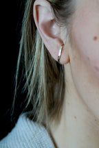 Close-up of an ear wearing a gold earring with a black background