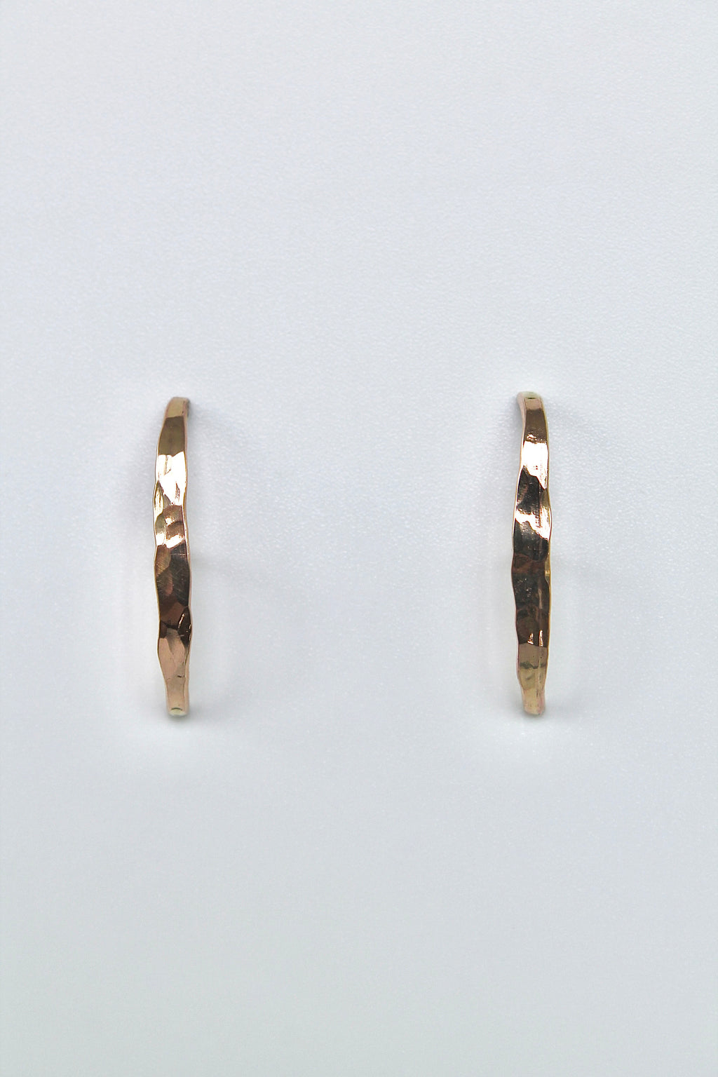 Gold stud earrings on a light gray background