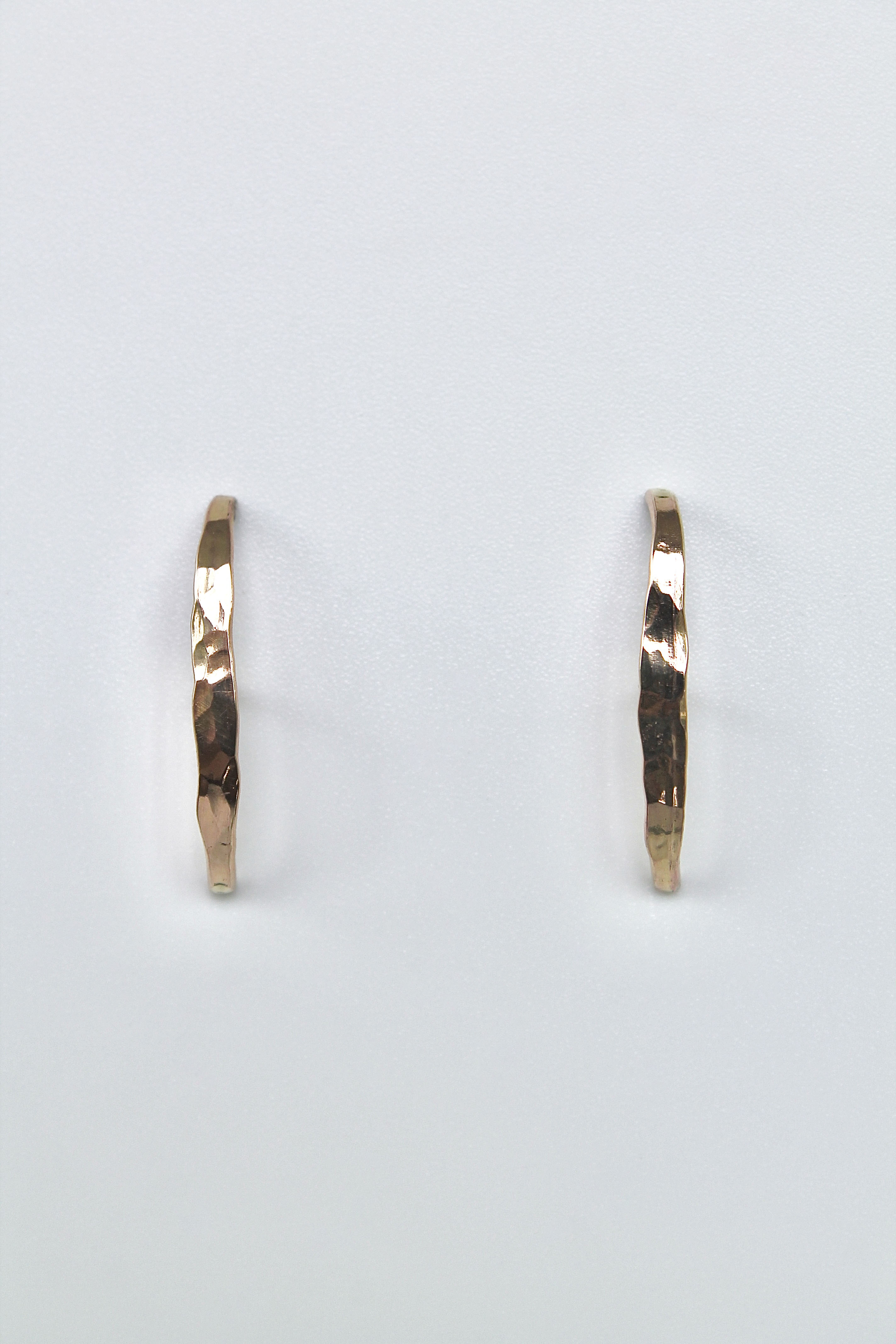 Gold stud earrings on a light gray background