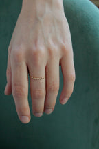 Hand wearing a gold fidget spinner ring on a green background