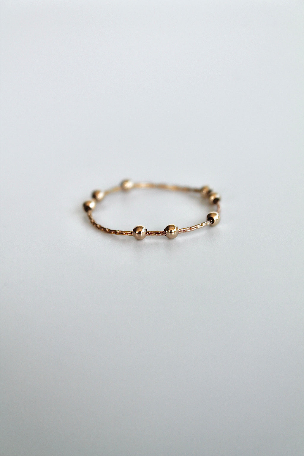 gold fidget spinner ring with gold beads on a white background