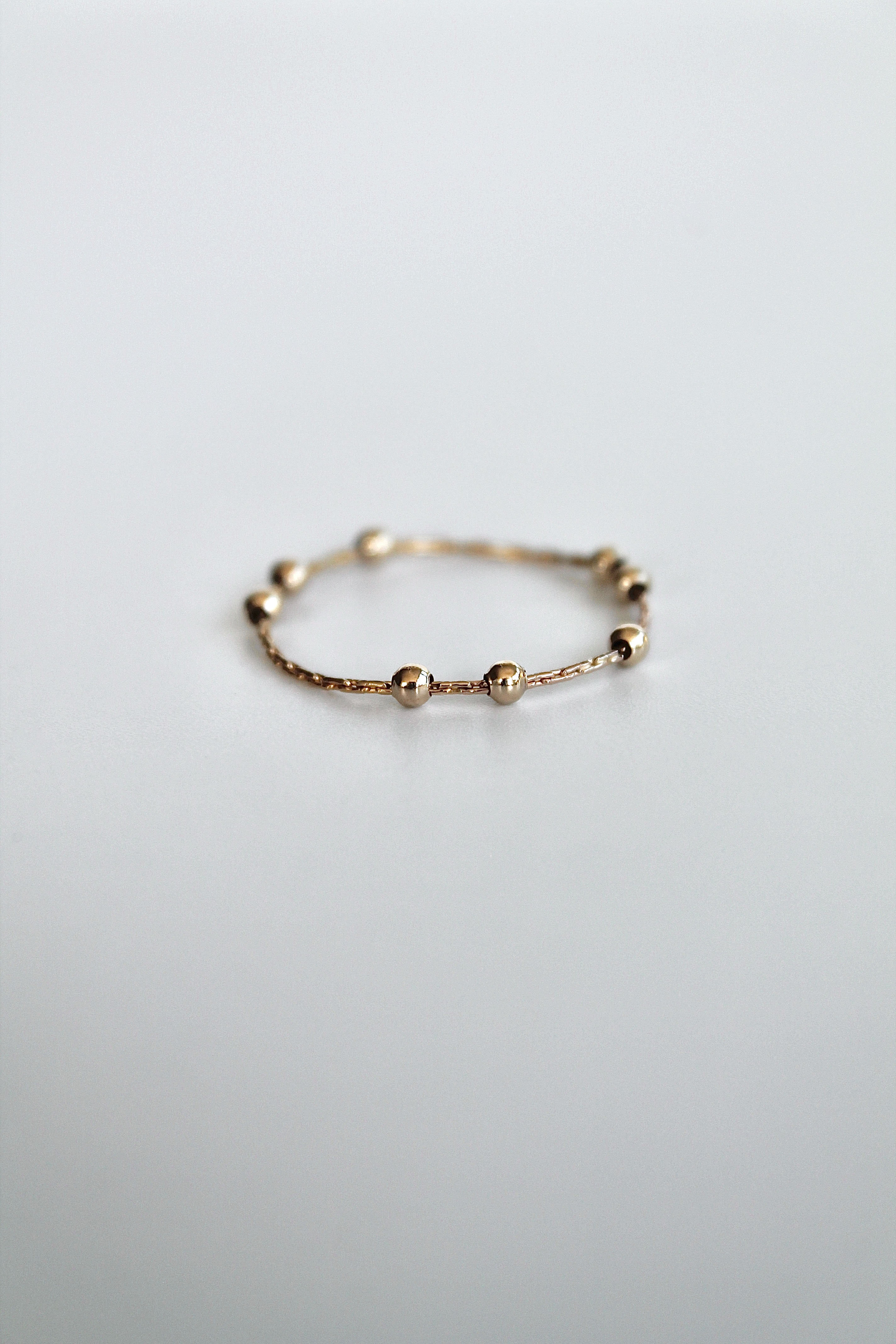 gold fidget spinner ring with gold beads on a white background