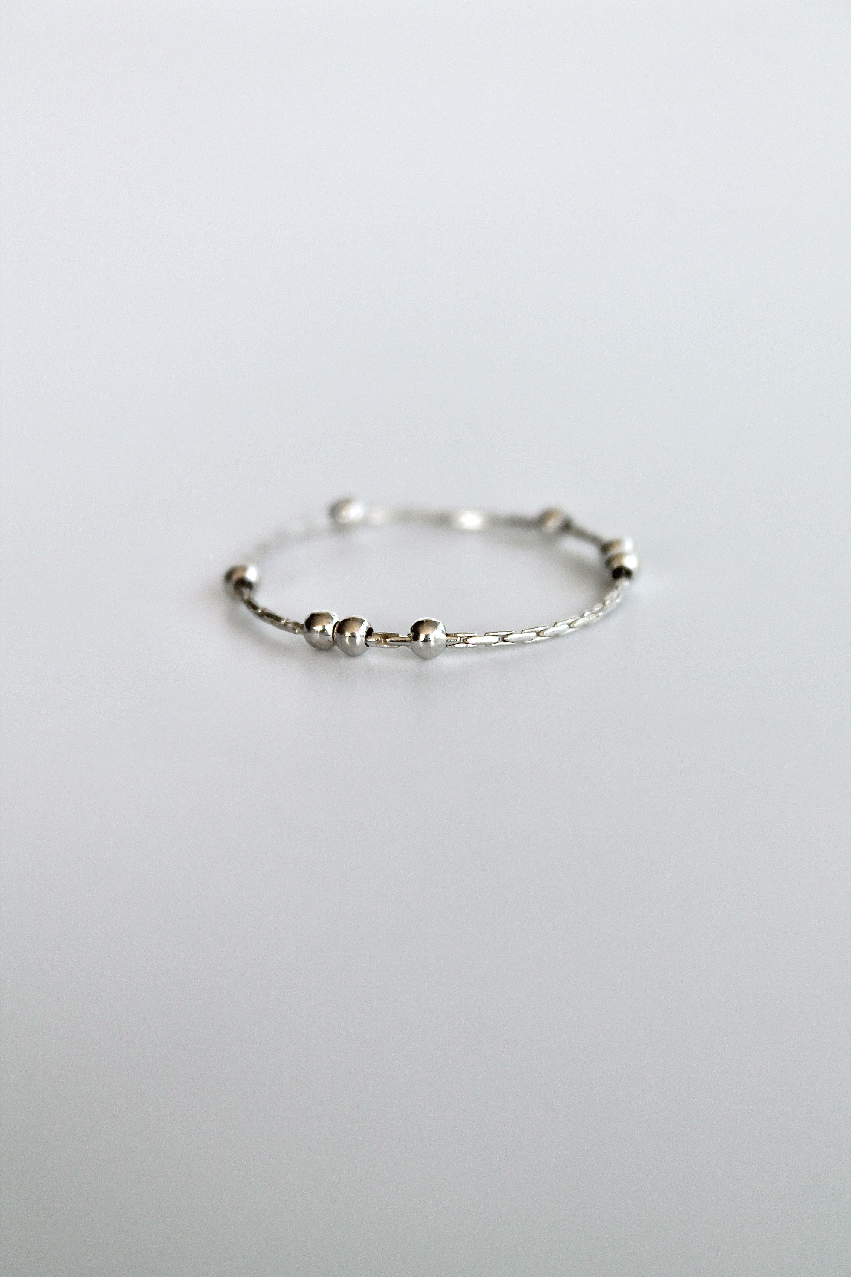 Silver fidget spinner ring with small silver beads on a white background