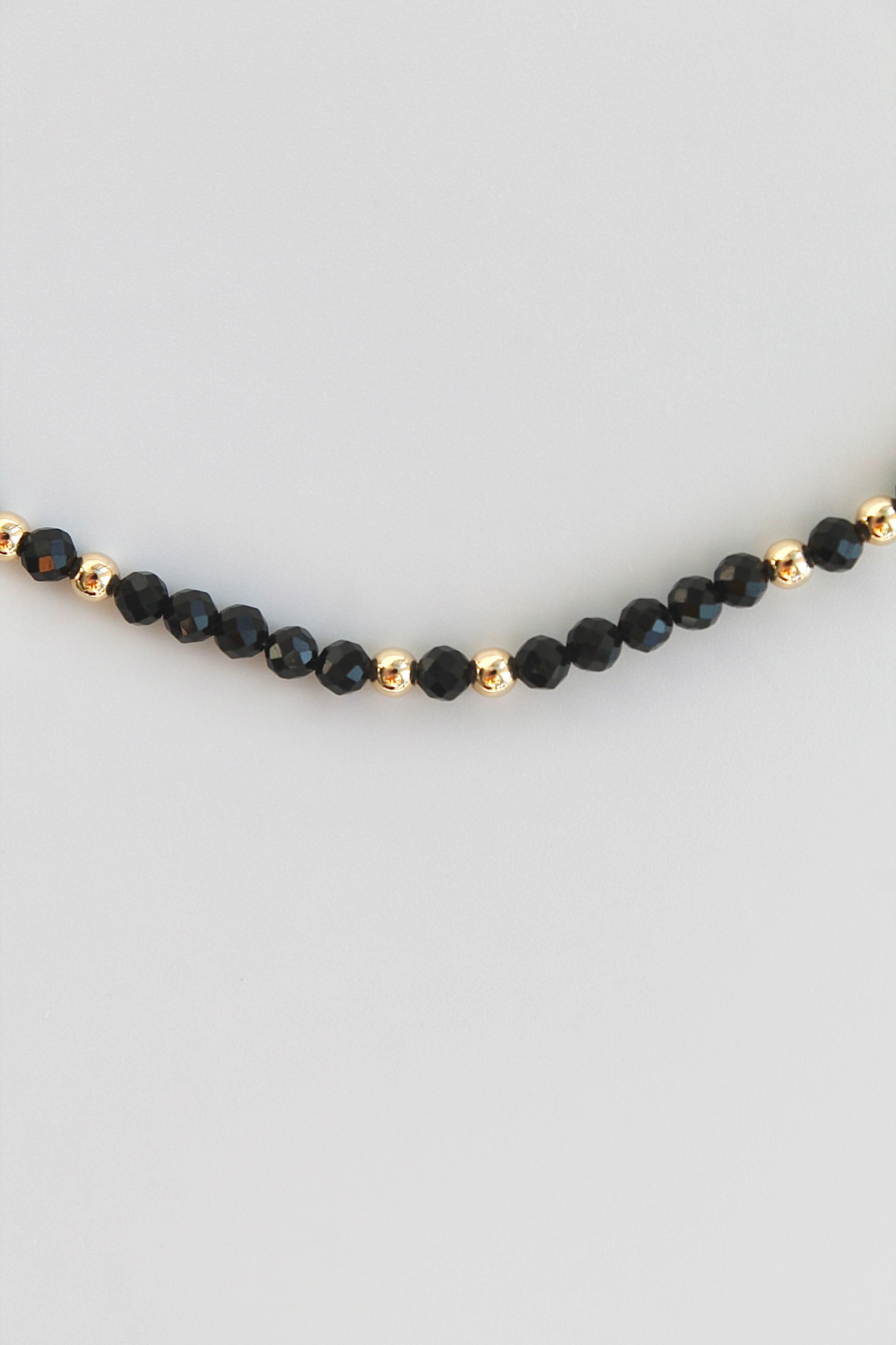 bracelet with black and gold beads on white background