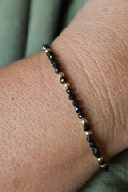 close-up of a black beaded bracelet on a wrist with green shirt background