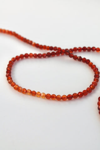 Close-up of a string of carnelian gemstone beads on a white background