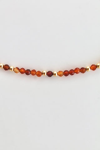 carnelian and gold bead bracelet on a white background
