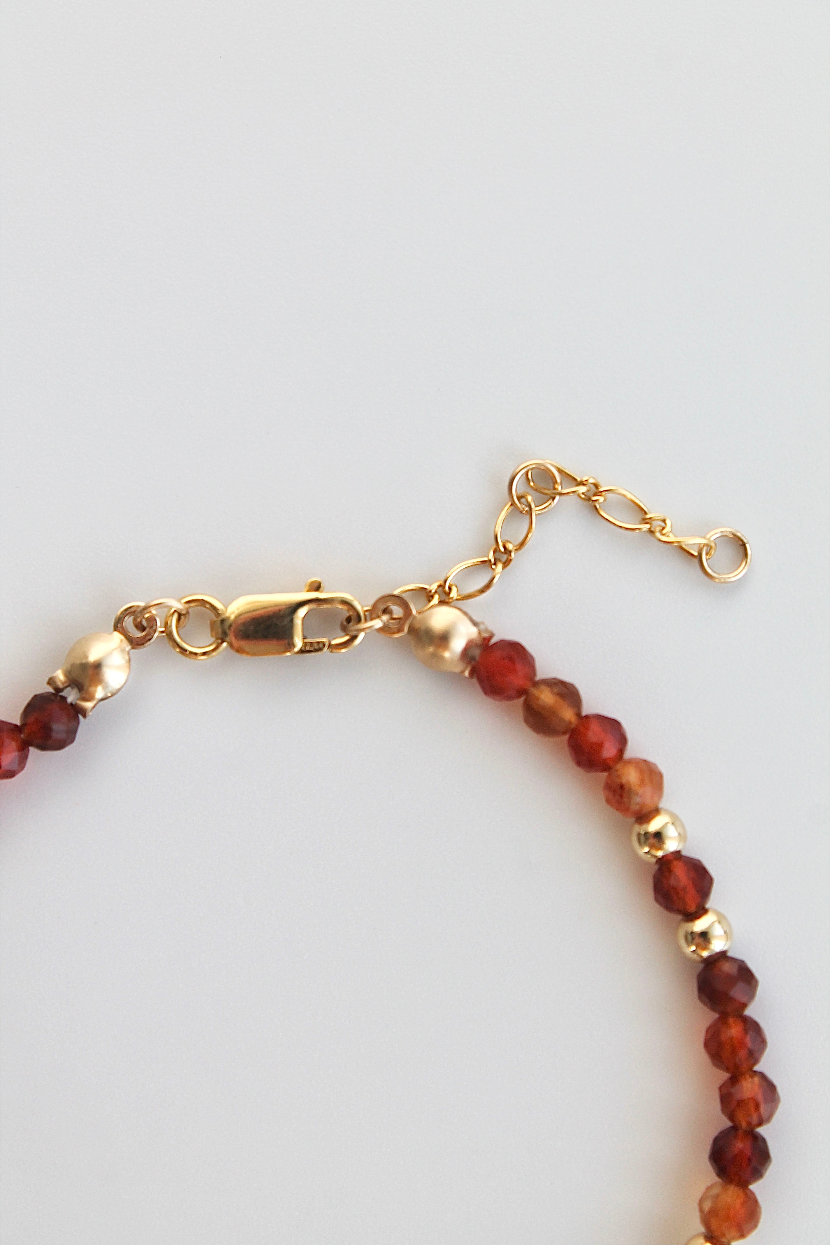 Bracelet with carnelian and gold beads and a gold clasp on a white background