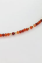 close-up of a carnelian and gold beaded bracelet on a white background