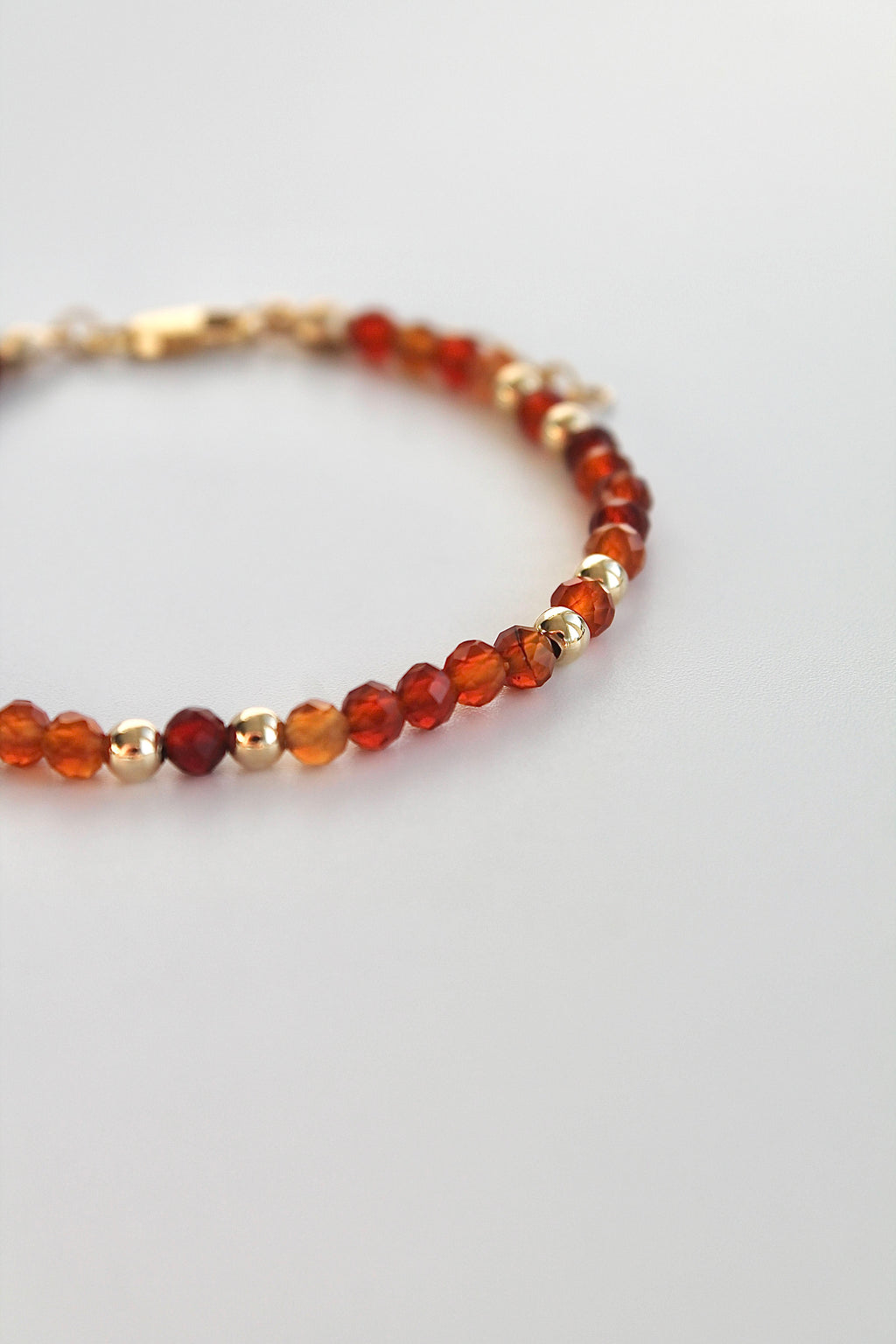 Bracelet with carnelian and gold beads on a white background
