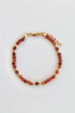 carnelian and gold beaded bracelet with gold clasp on a white background