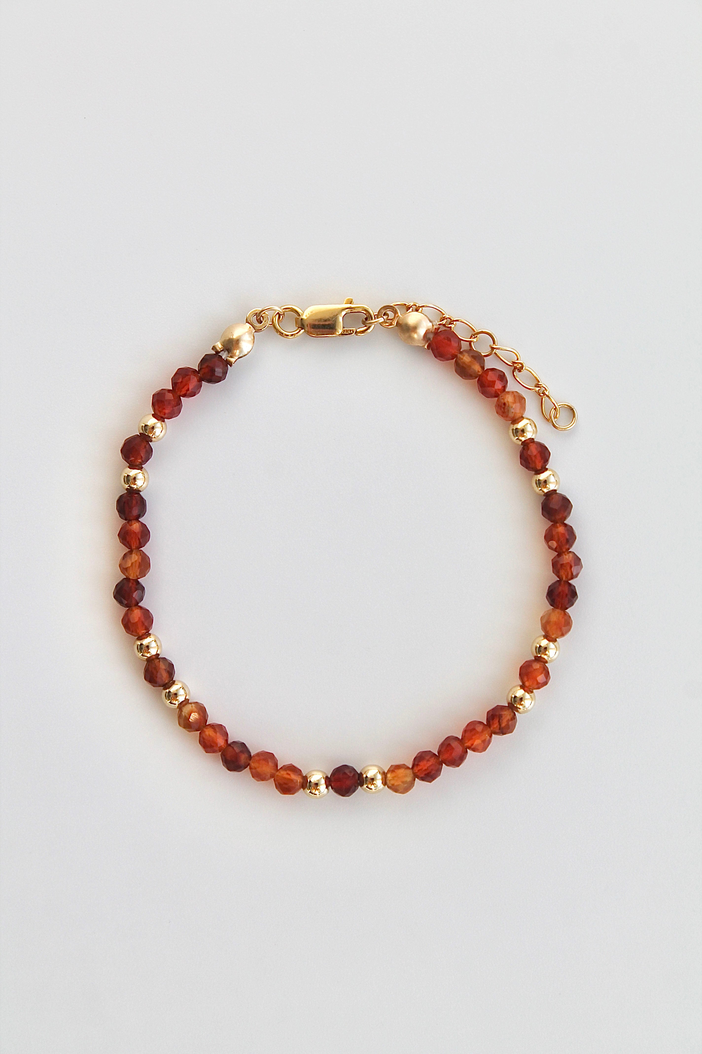 carnelian and gold beaded bracelet with gold clasp on a white background