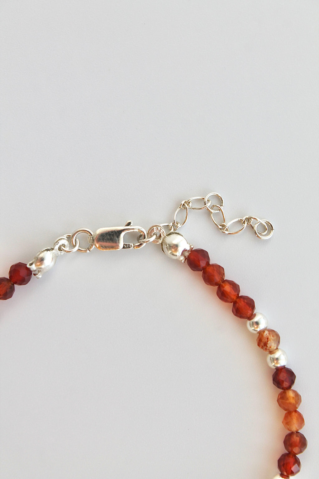 Bracelet with carnelian and silver beads and silver clasp on a white background