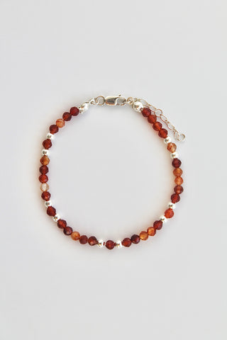Beaded bracelet with alternating carnelian and silver beads on a white background
