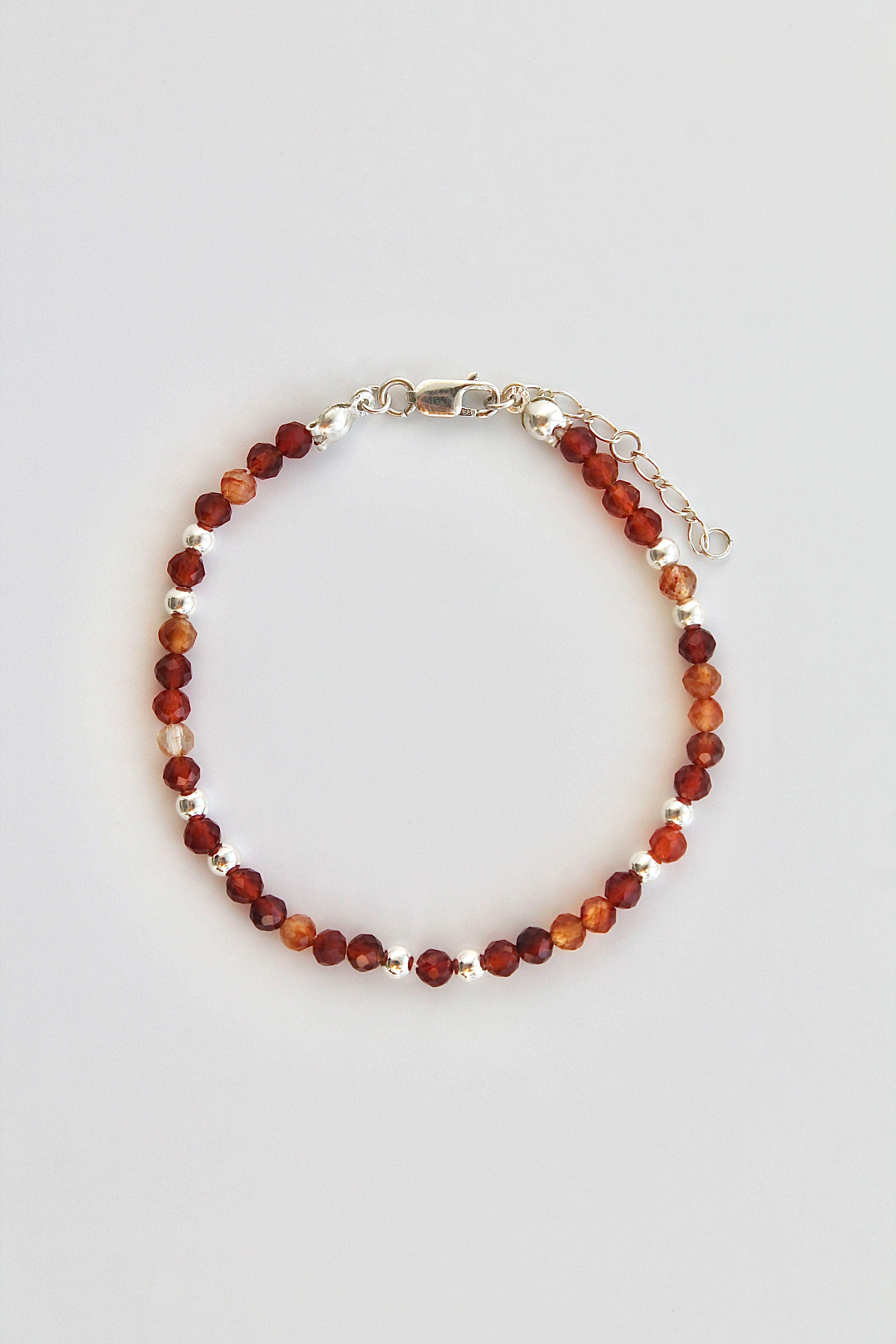 Beaded bracelet with alternating carnelian and silver beads on a white background