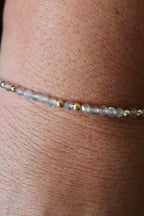 close-up of a labradorite gemstone and gold bead bracelet on a wrist