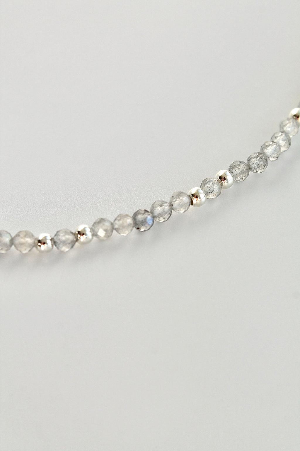 close-up of a labradorite gemstone and silver bead bracelet on a white background