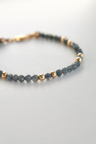 3mm sapphire gemstone and gold bead bracelet close-up on a white background