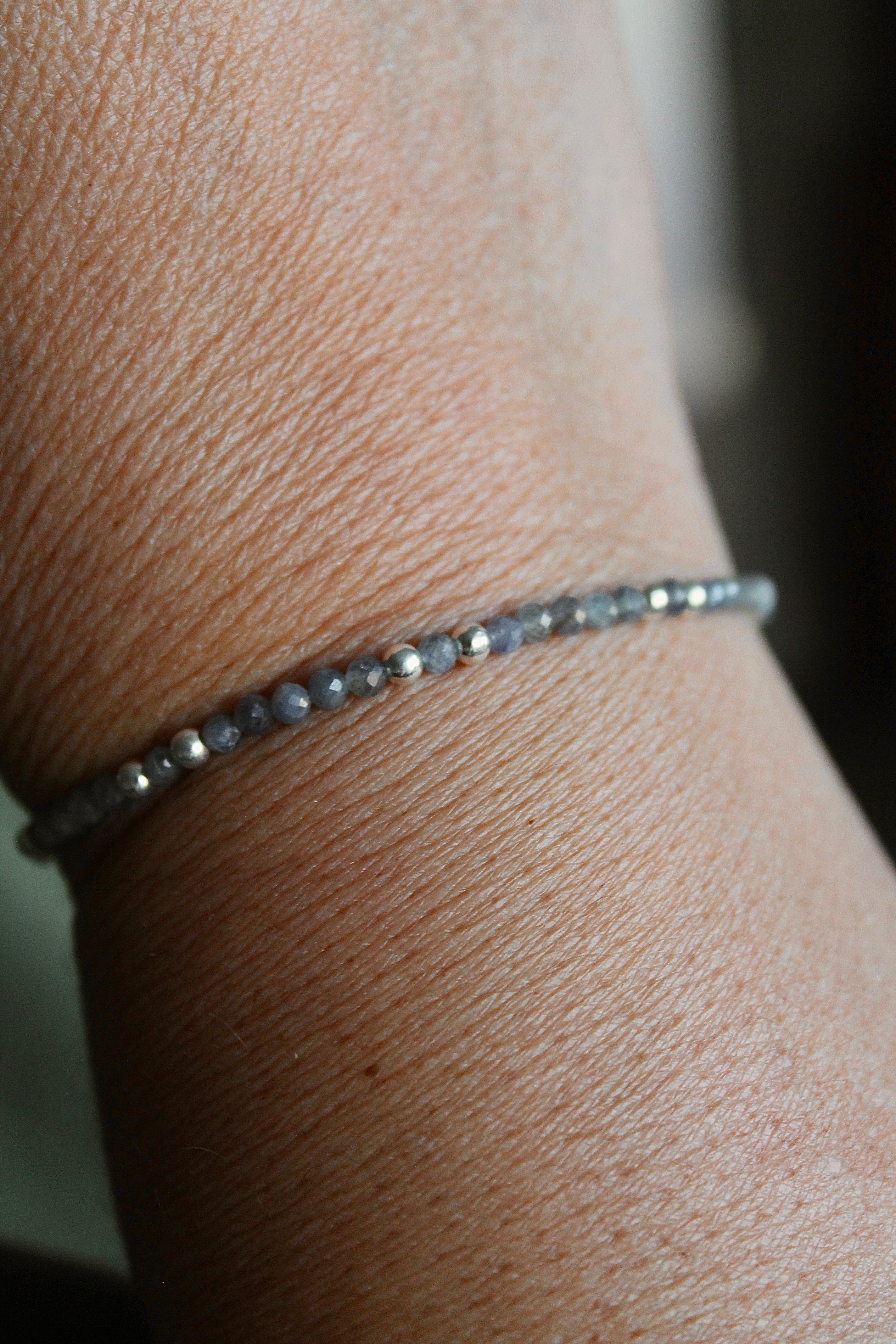 3mm sapphire gemstone silver bead bracelet close-up on a wrist with a blurred background