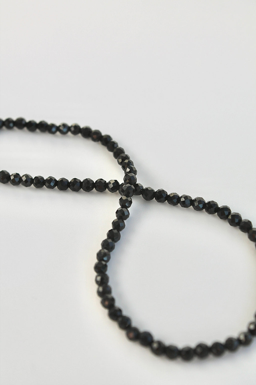 string of black tourmaline 3mm gemstones on a white background
