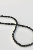 string of black tourmaline 3mm gemstones on a white background